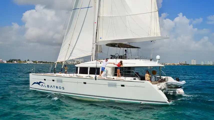 White luxury catamaran sailing from Cancun to Isla Mujeres with tourists relaxing on board.