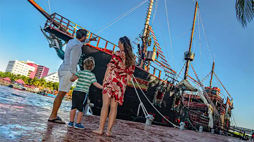 Family holding hands and facing a pirate ship, ready for the immersive pirate tour.