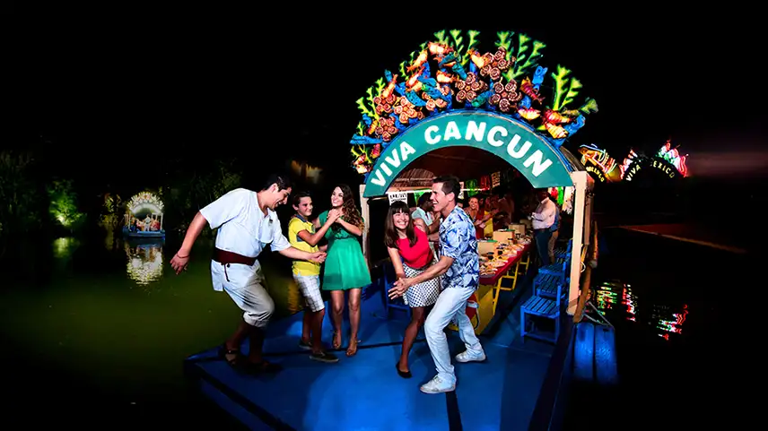 Friends enjoying the party in
a trajinera at Xoximilco Cancun, dancing and celebrating with a 'Viva Cancun' sign.