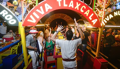 Group of friends having a
birthday party in a trajinera with a sign saying 'Viva Tlaxcala', dancing and enjoying the evening.